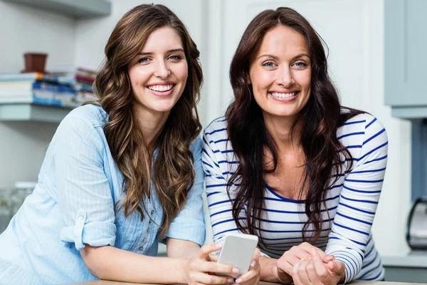 Female friends holding mobile phone — Stock Photo, Image