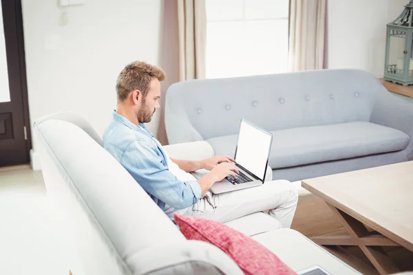 Hombre usando el ordenador portátil en el sofá en la habitación — Foto de Stock