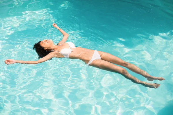 Mujer en bikini blanco flotando en la piscina — Foto de Stock