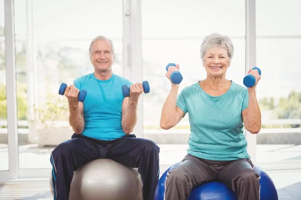 Portrait of smiling senior couple holding dumbbells — Stock Photo, Image