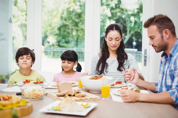 Familj med ögonen stängda på matbord — Stockfoto