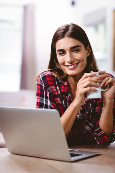Dizüstü bilgisayar ile kupa kahve tutan kadın — Stok fotoğraf