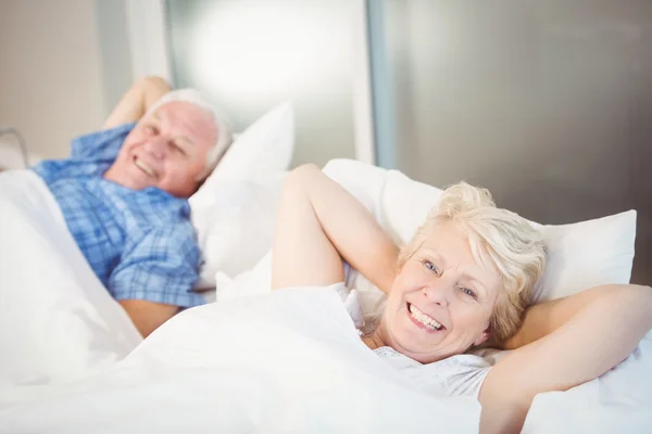 Senior vrouw ontspannen naast man op bed — Stockfoto