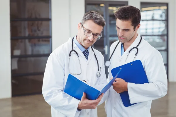 Médicos discutiendo mientras sostiene el portapapeles — Foto de Stock