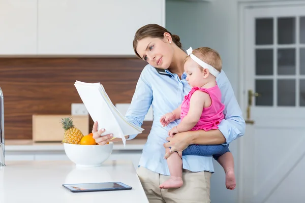 Frau liest Dokumente, während sie Baby trägt — Stockfoto