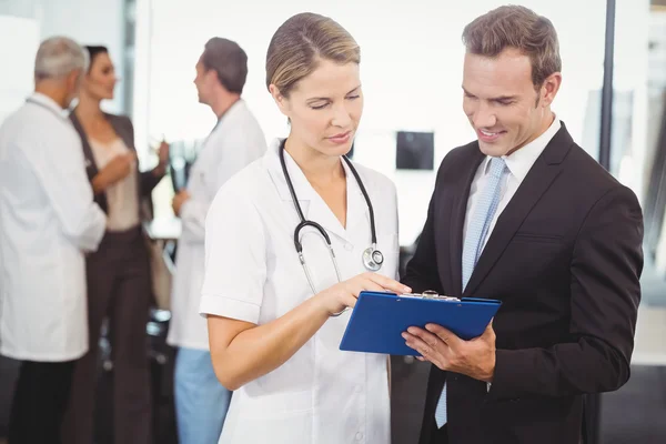 Doctors discussing report on clipboard — Stock Photo, Image