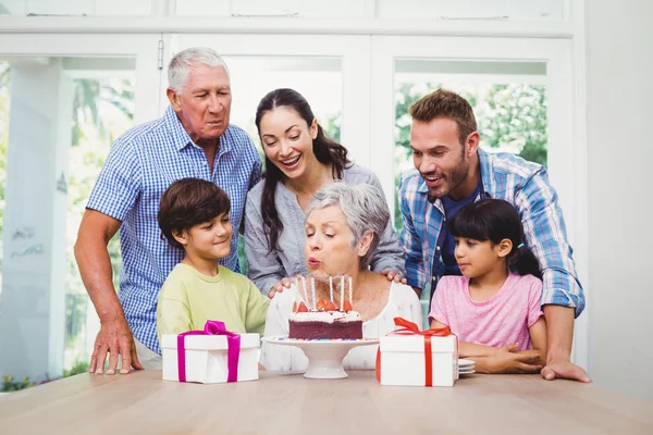 Babcia dmuchanie świeczki na urodzinowym torcie z rodziną — Zdjęcie stockowe