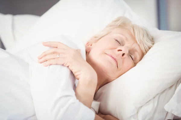 Seniorin schläft auf Bett — Stockfoto