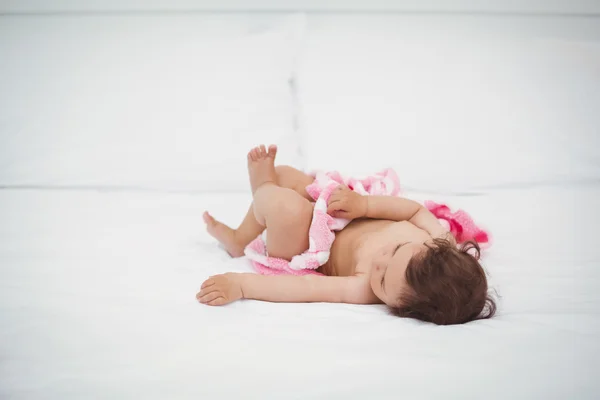 Baby holding blanket while lying on bed — Stock Photo, Image