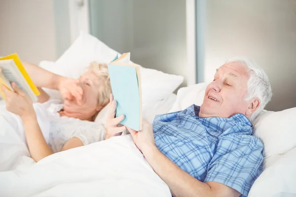 Couple reading while lying on bed — Stock Photo, Image