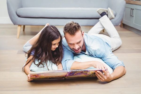 Padre e hija mirando en libro ilustrado — Foto de Stock