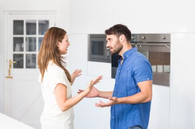 Couple arguing while standing in kitchen  clipart