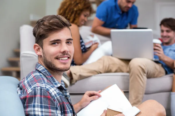 Man met boek terwijl vrienden op achtergrond — Stockfoto