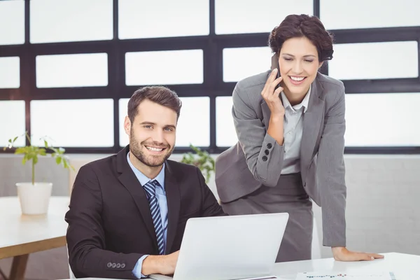 Business people with mobile phone and laptop in office — Stock Photo, Image