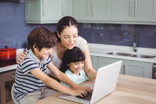 Madre e hijos que trabajan en el ordenador portátil — Foto de Stock