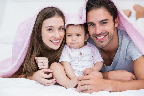 Retrato de pareja sonriente con bebé en la cama —  Fotos de Stock