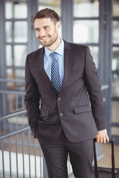 Businessman walking with luggage by railing — Stock Photo, Image