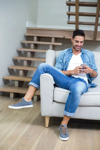 Człowiek za pomocą smartphone siedząc na kanapie — Zdjęcie stockowe