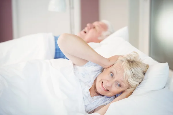 Vrouw blokkeert oren terwijl man snurken op bed — Stockfoto