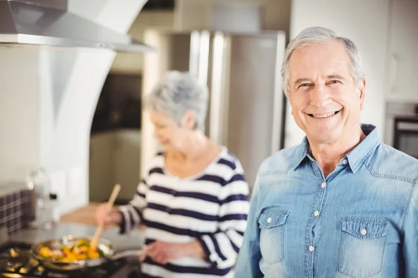 Uomo con donna cucina in background — Foto Stock