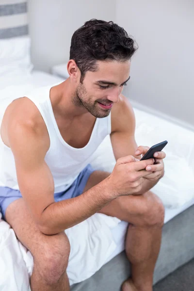 Man met mobiele telefoon op bed — Stockfoto