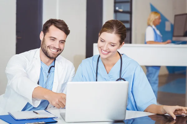 Médicos usando laptop enquanto discutem na mesa — Fotografia de Stock