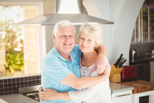 Портрет пожилой пары, обнимающейся на кухне — стоковое фото