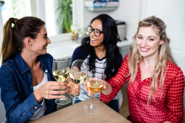 Vrienden roosteren wijnglazen aan tafel — Stockfoto