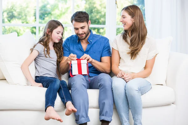 Uomo regalo di apertura mentre seduto sul divano — Foto Stock