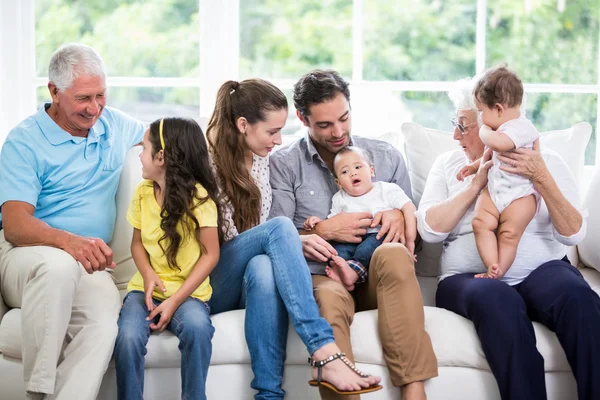 Family with grandparents sitting on sofa — Stock Photo, Image