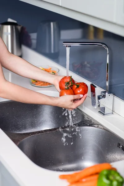 Женщина моет помидоры в раковине — стоковое фото