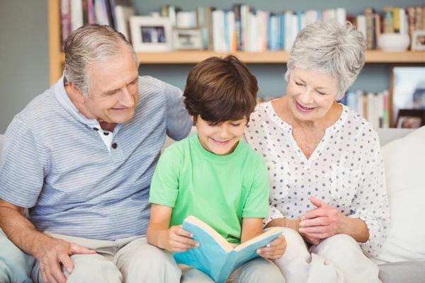 Grandparents assisting grandson reading book — Stock Photo, Image