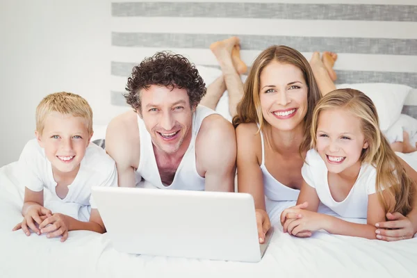 Famille en utilisant un ordinateur portable sur le lit — Photo