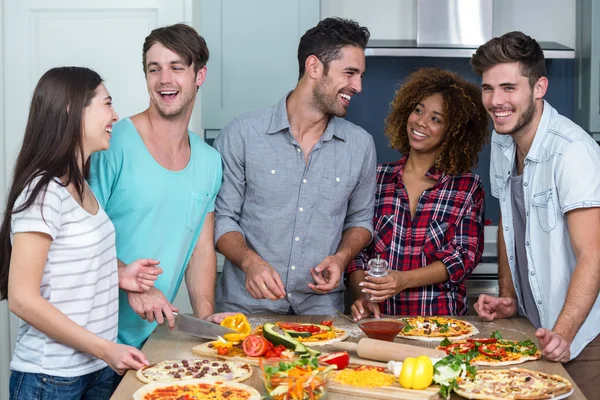 Amigos alegres preparando pizza en casa —  Fotos de Stock