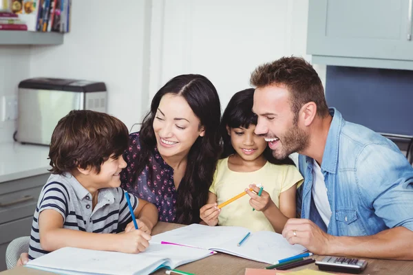 Glada föräldrar hjälpa barn i läxor — Stockfoto
