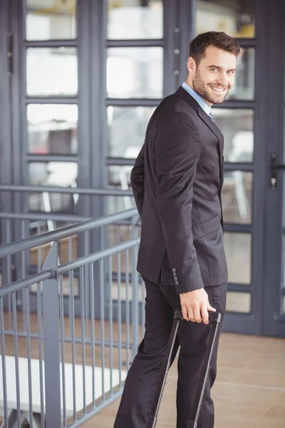 Businessman walking with luggage in office — Stock Photo, Image