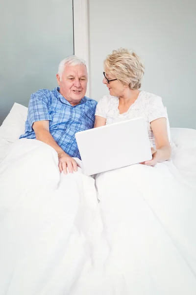 Casal sênior com laptop na cama — Fotografia de Stock