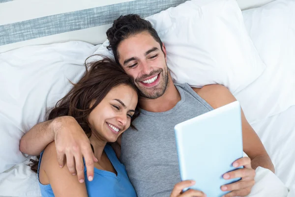 Para przy użyciu tabletu leżąc na łóżku — Zdjęcie stockowe