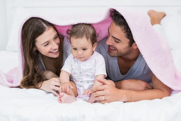 Pareja disfrutando con el bebé bajo la manta en la cama —  Fotos de Stock