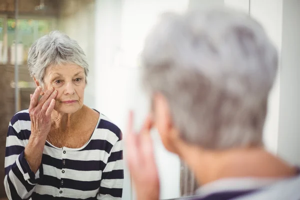 Reflektion av senior kvinna som tittar på huden i spegeln — Stockfoto