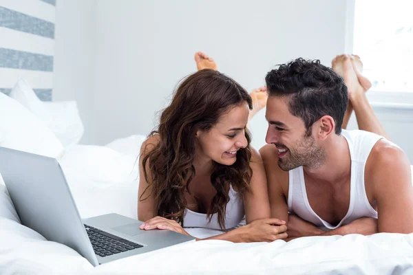 Casal com laptop enquanto deitado sob cobertor — Fotografia de Stock