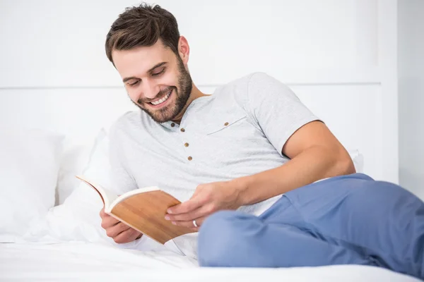 Человек читает книгу на кровати — стоковое фото