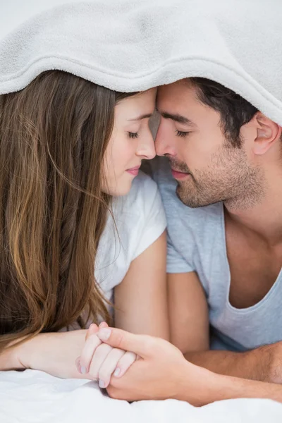 Nahaufnahme eines Paares, das sich unter einer Decke auf dem Bett räkelt — Stockfoto