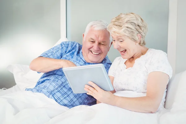 Excited senior couple using digital tablet at home — Stock Photo, Image