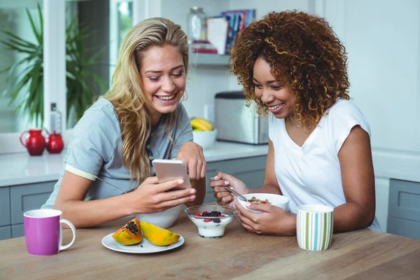Друзья смотрят в мобильный телефон во время завтрака — стоковое фото