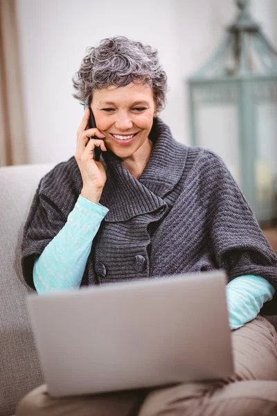 Donna con laptop utilizzando il telefono cellulare — Foto Stock