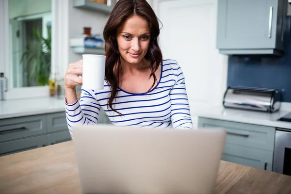 Kvinna som arbetar på laptop i köket — Stockfoto