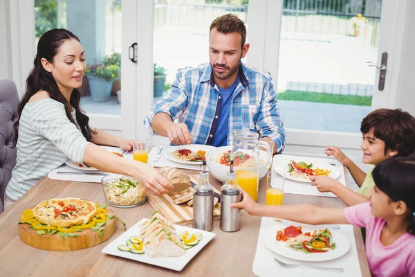 Ter comida enquanto está sentado à mesa de jantar — Fotografia de Stock