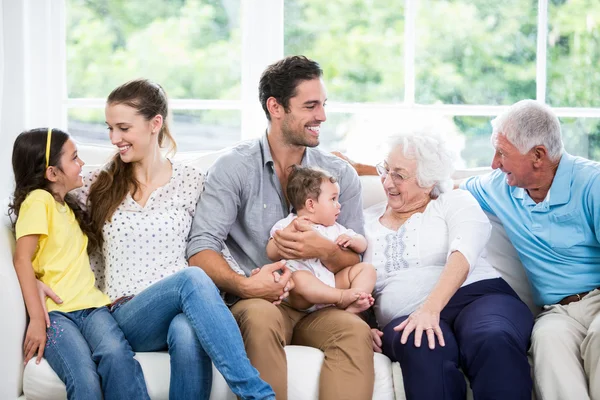 Семья с бабушкой и дедушкой, сидящие на диване — стоковое фото