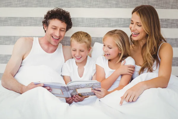 Family reading book on bed — Stock Photo, Image